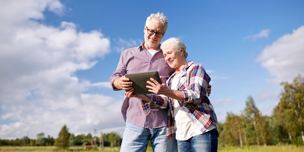 a middle aged couple in a field looking at a tablet
